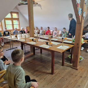 Dzieci z uwagą słuchają pana Krzysztofa opowiadającego o tradycyjnym sposobie kiszenia kapusty