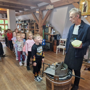 Dzieci ustawione w kolejkę czekają na podjęcie próby szatkowania kapusty szatkownicą 