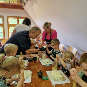 Dzieci z pomocą wychowawczyni  i pana Krzysztofa ubijają kapustę w słoikach 