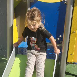 Dziewczynka zjeżdża na zjeżdżalni.