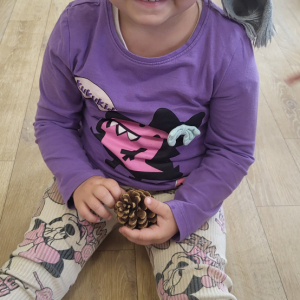 Dziewczynka trzymająca szyszkę.