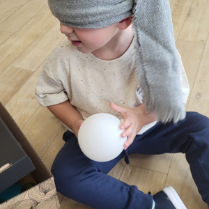 Chłopiec próbuje odgadnąć co wylosował przy pomocy zmysłu dotyku.