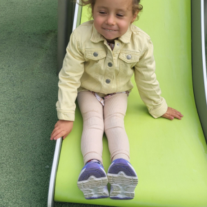 Dziewczynka zjeżdża na zjeżdżalni.