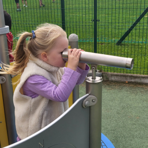 Dziewczynka spoglądająca przez lunetę.
