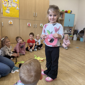 Dziewczynka pokazuje jak przełożyła robaczka przez środek jabłka 