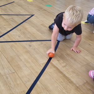 Chłopiec turlający piłeczkę po torze.