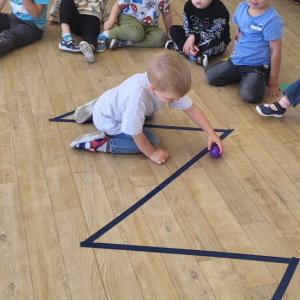 Chłopiec turlający piłeczkę po torze.