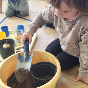 Dziewczynka wsypuje ziemię do doniczki.