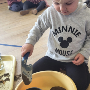 Dziewczynka wsypuje ziemię do doniczki.