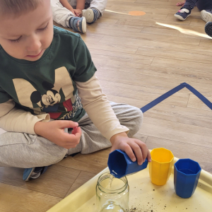 Chłopiec przelewa wodę.