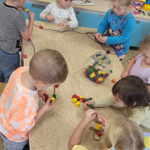 Dzieci nawlekające koraliki na sznurki.