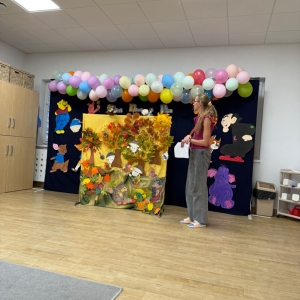 Nauczycielka na tle scenografii do teatrzyku pacynkowego pod tytułem Czerwony Kapturek