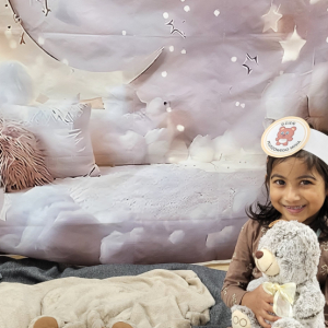 Dziewczynka pozująca na przygotowanej ściance fotograficznej.