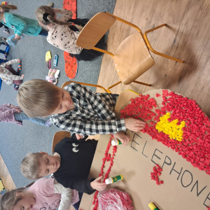 Dziecko wykleja angielska budkę telefoniczną kolorową bibułą