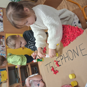 Dziecko wykleja angielska budkę telefoniczną kolorową bibułą