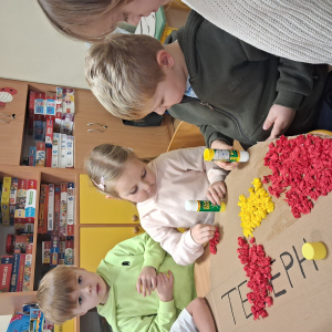 Dziecko wykleja angielska budkę telefoniczną kolorową bibułą