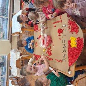 Dziecko wykleja angielska budkę telefoniczną kolorową bibułą