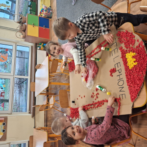 Dziecko wykleja angielska budkę telefoniczną kolorową bibułą