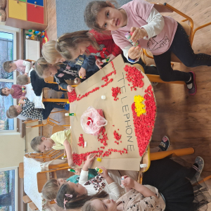 Dziecko wykleja angielska budkę telefoniczną kolorową bibułą