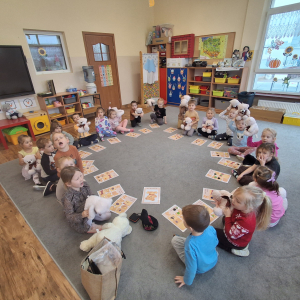 Dzieci siedzą w kole i graja w misiowe Bingo