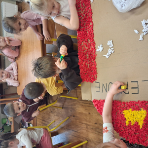 Dziecko wykleja angielska budkę telefoniczną kolorową bibułą