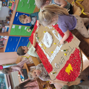 Dziecko wykleja angielska budkę telefoniczną kolorową bibułą