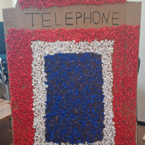 Dziecko wykleja angielska budkę telefoniczną kolorową bibułą