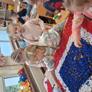 Dziecko wykleja angielska budkę telefoniczną kolorową bibułą