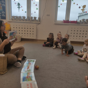 dzieci siedzą na dywanie i słuchają bajki o jeżyku