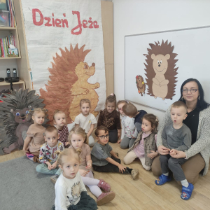 dzieci siedzą na tle jeży