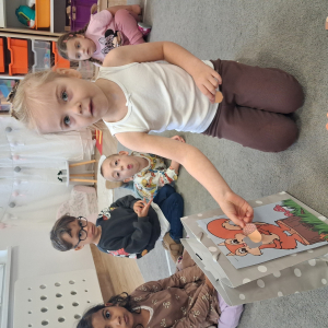 dziecko karmi wiewiórkę obrazkami przedstawiającymi słownictwo jesienne