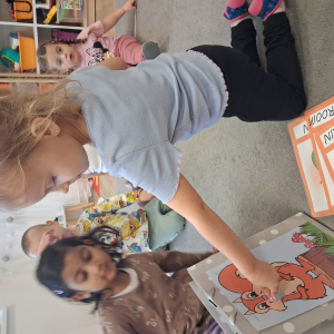 dziecko karmi wiewiórkę obrazkami przedstawiającymi słownictwo jesienne