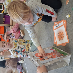 dziecko karmi wiewiórkę obrazkami przedstawiającymi słownictwo jesienne