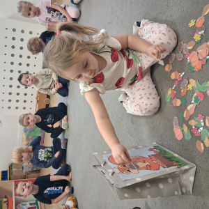 Dziecko trzyma w dłoni obrazek o tematyce jesiennej