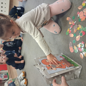 Dziecko trzyma w dłoni obrazek o tematyce jesiennej