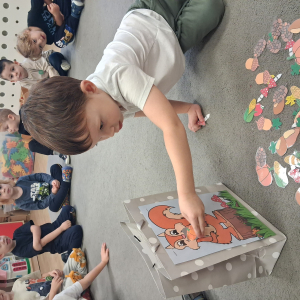 Dziecko trzyma w dłoni obrazek o tematyce jesiennej