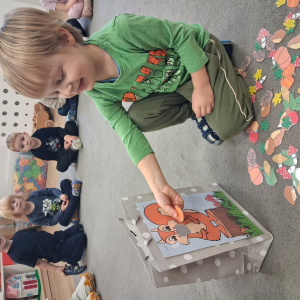 Dziecko trzyma w dłoni obrazek o tematyce jesiennej