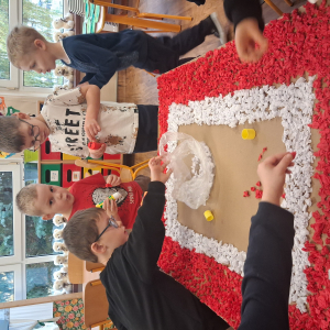 Dziecko wykleja angielska budkę telefoniczną kolorową bibułą