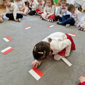 Dziewczynka układa flagę Polski z pasków papieru