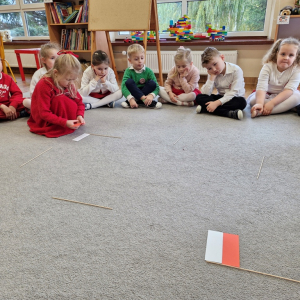 Dziewczynka układa flagę Polski z pasków papieru