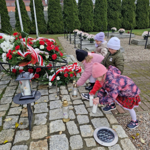 Dzieci kładą zapalone znicze przy Pomniku Ofiar Zbrodni Hitlerowskich w latach 1039-1945