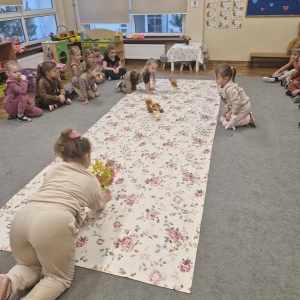 Dziewczynki układają na obrusie wazony z kwiatami