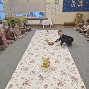 Chłopiec kładzie na obrusie dekorację ze   świeczką