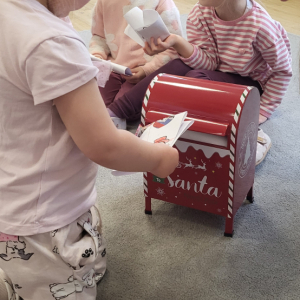 Dziewczynka wrzucająca list do skrzynki. 