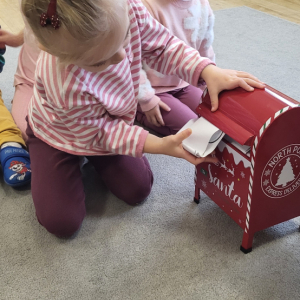 Dziewczynka wrzucająca list do skrzynki. 