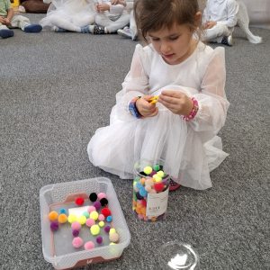 dziewczynka próbuje złapać pomponik klamerką