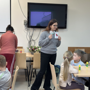 Pomoc i tłumaczenie: „Instruktor WTZ tłumaczy kolejne etapy tworzenia kartki, a dzieci chętnie słuchają i próbują samodzielnie.”