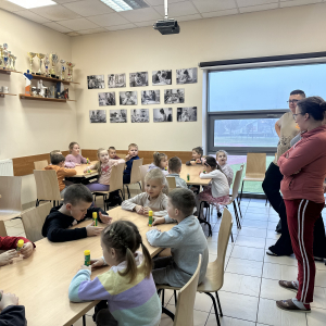 Pomoc i tłumaczenie: „Instruktor WTZ tłumaczy kolejne etapy tworzenia kartki, a dzieci chętnie słuchają i próbują samodzielnie.”
