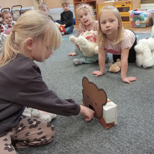 dziewczynka "karmiąca" misia ciasteczkami zgodnie z wyrzuconą liczbę oczek na kostce