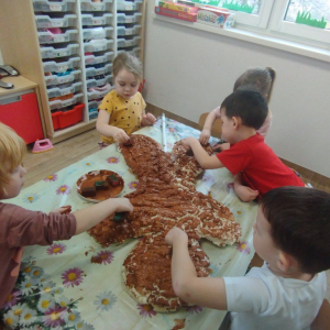 Dzieci malują farbami piernika zrobionego z pianki uszczelniającej.